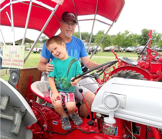 Stacy Pearson, of Siloam Springs, and grandson Summit Smugala, 4, Sit on an antique Ford tractor at the Tired Iron of the Ozarks fall show in Gentry on Friday.