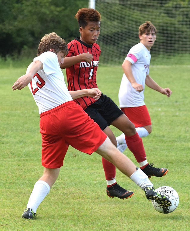 Rick Peck/Special to McDonald County Press McDonald County's Kaw Htoo and Carl Junction's Caleb Gau fight for control of a loose ball during the Bulldogs' win in penalty kicks on Sept. 6 at MCHS.