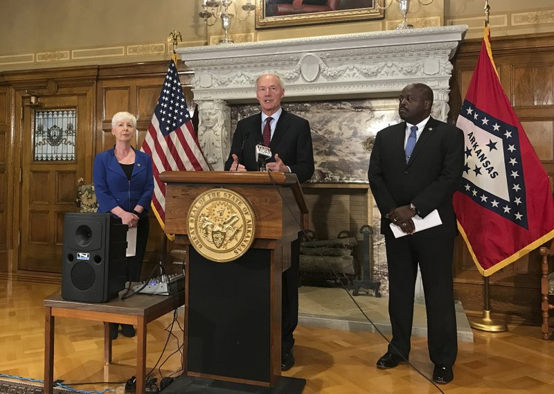 Arkansas Gov. Asa Hutchinson, center, talks at a news conference at the State Capitol in Little Rock on Wednesday about the state's work requirement for its expanded Medicaid program. Officials said more than 4,300 people on the program lost coverage for not meeting the new work requirement. (AP Photo/Andrew DeMillo)

