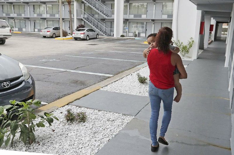 Idalis Fernandez carries her 2-year-old son Adrian to their FE- MA-provided hotel room in Kissimmee, Fla., earlier this week. Vouchers that she and other Puerto Rican evacuees have been using to pay for housing will expire today. 