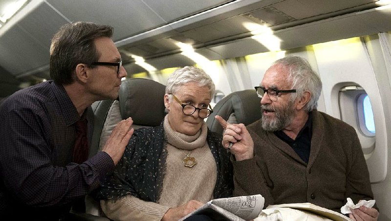 Nathaniel Bone (Christian Slater) says hello to Joan (Glenn Close) and Joe Castleman (Jonathan Pryce) as they fly across the Atlantic to pick up Joe’s Nobel Prize for Literature in the sly black comedy The Wife.
