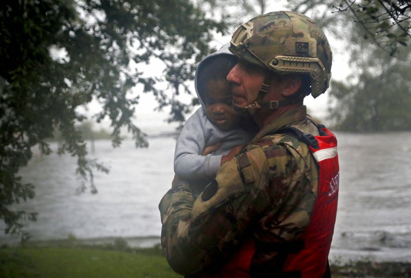 Rescue team member Sgt. Nick Muhar, from the North Carolina National Guard 1/120th battalion, evacuates a young child as the rising floodwaters from Hurricane Florence threatens his home in New Bern, N.C., on Friday, Sept. 14, 2018. (AP Photo/Chris Seward)