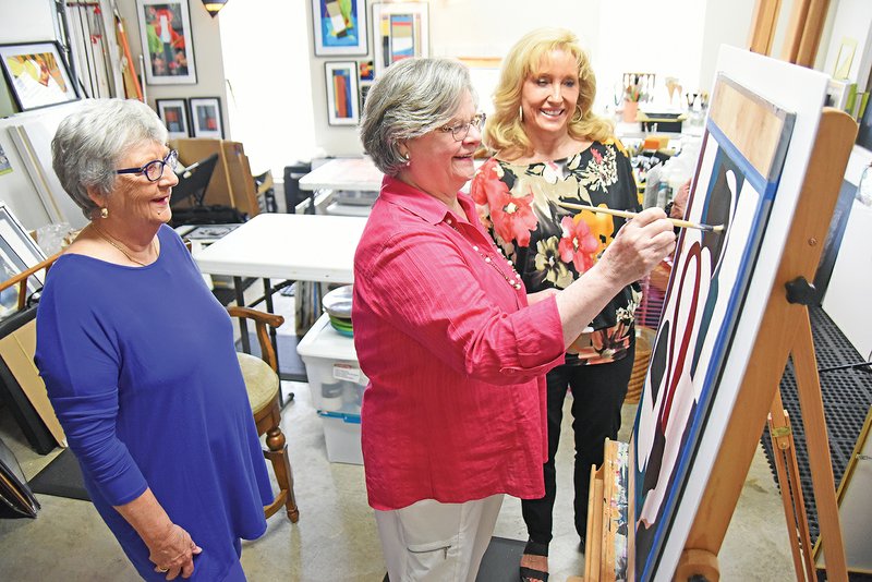 Judith Beale, center, works on a painting in her home studio in Jacksonville as her friends and fellow artists Sandra Marson of Jacksonville, left, and Charlotte Rierson of Fairfield Bay encourage Beale. The three artists were friends in high school and have reconnected through their love of art.