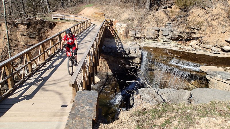 Kelly Williams, director of the FAST National Mountain Bike Patrol, crosses a creek along the Back 40 trail system in Bella Vista. Patrol members assist riders with bike repair and first aid.