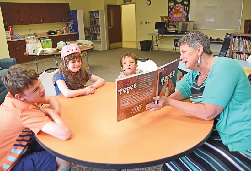 Sally Paine, right, executive director of The Sunshine School in Searcy, reads a book about Native Americans to, from left, Braiden Wortham, 13, Alexa Williams, 13, and Braden Milatz, 14. In addition to her duties as executive director of the school, Paine plans to go into classrooms and read to students.