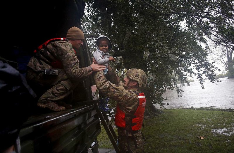 Sgt. Matt Locke (left) and Sgt. Nick Muhar with the North Carolina National Guard help a child Friday as rising floodwaters from Hurricane Florence threaten the family’s home in New Bern, N.C. 