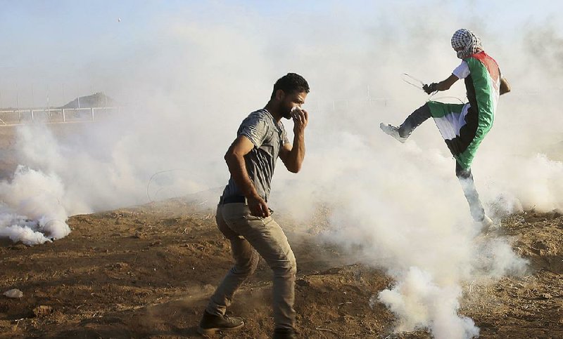 Palestinian protesters endure blasts of tear gas fired Friday by Israeli troops during clashes at the Gaza Strip border fence. 