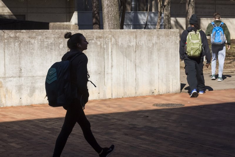 FILE — Students are silhouetted by the morning sun as they walk past UALR's Ottenheimer Library in this 2017 file photo.

