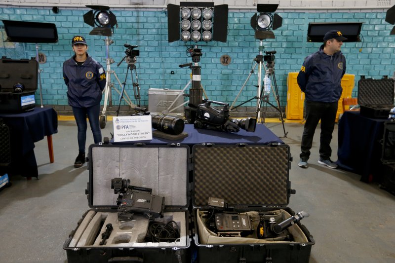 Police next to stolen film equipment during a media presentation at the police department in Buenos Aires, Argentina, Friday, Sept. 14, 2018. Argentine authorities say they have seized about $3 million in cameras, lenses and other film equipment stolen in Hollywood and New York. (AP Photo/Natacha Pisarenko)