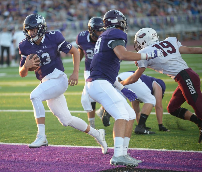 NWA Democrat-Gazette/ANDY SHUPE Elkins quarterback Quinn McClain (23) carries the ball into the end zone past Huntsville safety Justin Reynolds (19) Friday, Sept. 14, 2018, for the first varsity touchdown at the newly dedicated John Bunch Jr. Stadium in Elkins. Visit nwadg.com/photos to see more photographs from the game.