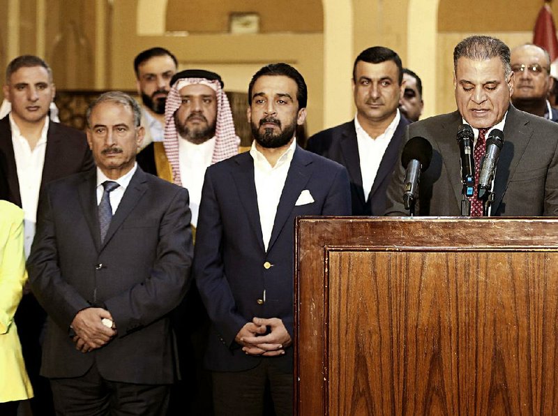 Mohammed al-Halbousi (center), Iraq’s new speaker of parliament, stands with other members of his political bloc at a Friday news conference. 
