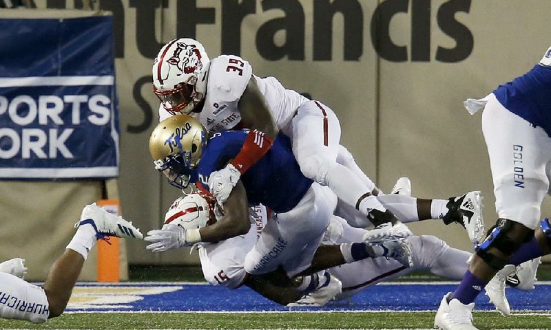 Arkansas State’s Dajon Emory (top) and Kevin  Thurmon tackle Tulsa’s Keylon Stokes for a safety during Saturday night’s game in Tulsa. 
