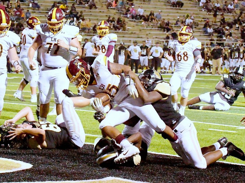 The Sentinel-Record/Grace Brown STILL RUNNING: Lake Hamilton junior fullback Dealond Lewis (15) is taken down by Hot Springs' Malik Cooper (64) and Eddie Miles (14) as he makes his way into the end zone Friday night at Tommy J. Holt Field at Joe C. Reese Stadium. Lewis had seven carries for 45 yards and two touchdowns in the Wolves' 42-7 win.