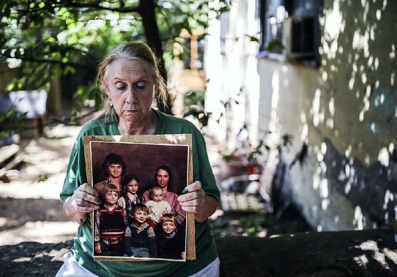 Julia Collins holds a portrait of her family at her home in Little Rock on Saturday. All four of her sons have struggled with drug abuse, including two who have died.