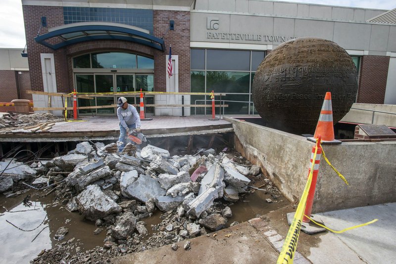 NWA Democrat-Gazette/J.T. WAMPLER Sergio Flores of Springdale uses a saw to cut iron rebar Wednesday while demolishing the front stairs at the Town Center on the Fayetteville square. The center just wrapped an interior renovation to increase its rentable space, adopted a new website and has plans for several upcoming events, among other recent efforts its staff has undertaken. The city is installing new stairs in front of the building because they sank about three inches due to leaking from the World Peace Fountain.