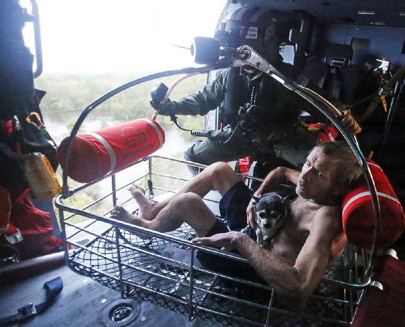 Willie Schubert is hoisted aboard a U.S. Coast Guard helicopter after he was rescued off a stranded van Monday in Pollocksville, N.C.
