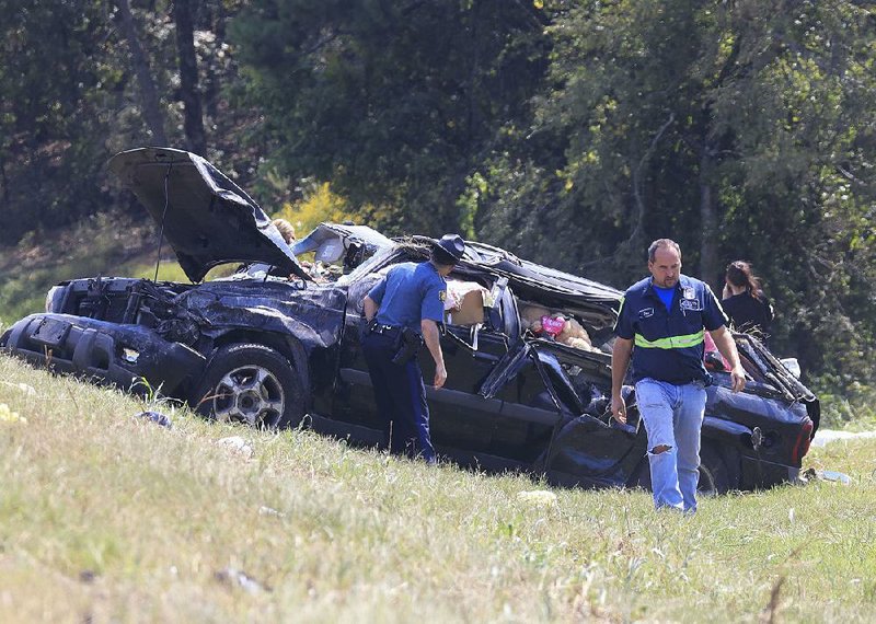 Emergency personnel work Monday afternoon at the scene of a fatal single car accident in the Interstate 40 and Interstate 430 interchange. Two people were injured, according to an Arkansas State trooper on the scene.