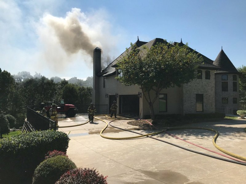 Courtesy/FAYETTEVILLE FIRE DEPARTMENT Firefighters work Monday to extinguish at fire at a home near Blessings Golf Club in Johnson.