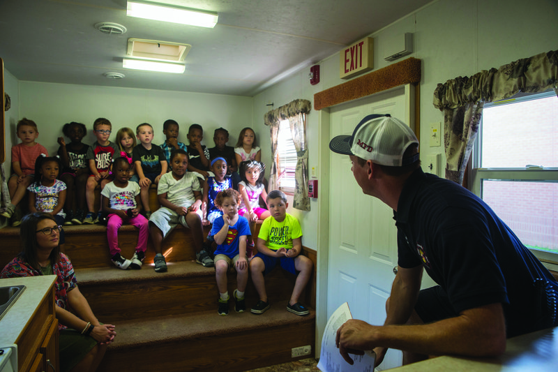 Magnolia Fire Department (MFD) Lieutenant Hayden Collier (right) shows Mrs. Pinner’s kindergarten class how to evacuate a smoke-filled room.