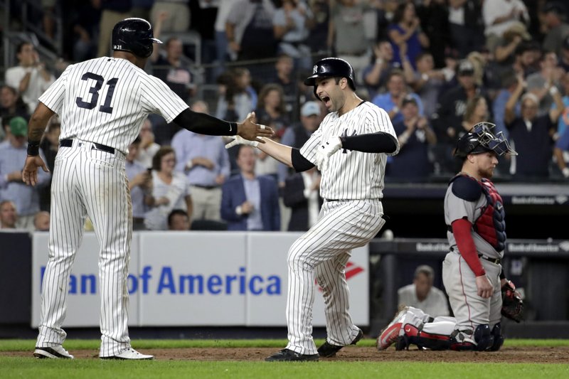New York Yankees' Neil Walker, right, celebrates with Aaron Hicks (31) after hitting a three-run home run off Boston Red Sox relief pitcher Ryan Brasier during the seventh inning of a baseball game Tuesday, Sept. 18, 2018, in New York. Red Sox catcher Christian Vazquez is at right. (AP Photo/Julio Cortez)