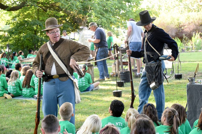 NWA Democrat-Gazette/FLIP PUTTHOFF Kerry Jones (left) and Troy Banzhaf show students Tuesday rifles and gear carried by Civil War soldiers. Their talk was part of a living history program for area fourth-grade students at Peel Mansion in Bentonville. The Peel Compton Foundation hosted 1,000 fourth-grade students from area schools who a taking park in hand-on exhibits and programs. Foundation volunteers and mansion staff dressed in 19th century garb to teach the students what life was like in the 1800s.The mansion was built in 1875 by Colonel Samuel West Peel. It is open for viewing and tours Tuesday through Saturday from 10 a.m. to 3 p.m. Jones and Banzhaf are both rangers at Pea Ridge National Military Park east of Pea Ridge.