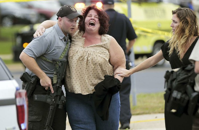 A woman is escorted from the scene of a Wednesday shooting at a software company in Middleton, Wisc., in which four people were wounded. 
