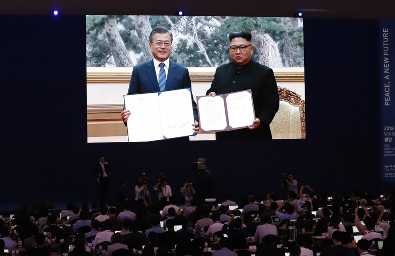 Members of media watch a huge screen showing South Korean President Moon Jae-in, left, and North Korean leader Kim Jong Un hold documents after signing in Pyongyang, North Korea, at a press center for the inter-Korean summit in Seoul, South Korea, Wednesday, Sept. 19, 2018. (AP Photo/Lee Jin-man)