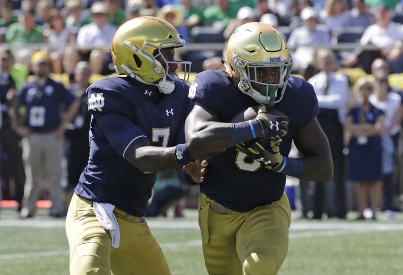 Notre Dame quarterback Brandon Wimbush, left, drops off the ball to running back Tony Jones Jr., during the first half of an NCAA college football game against Vanderbilt in South Bend, Ind., Saturday, Sept. 15, 2018. (AP Photo/Nam Y. Huh)