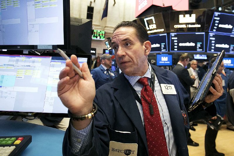 Trader Tommy Kalikas works Thursday on the floor of the New York Stock Exchange. The Dow Jones industrial average closed above its previous record reached in January. 
