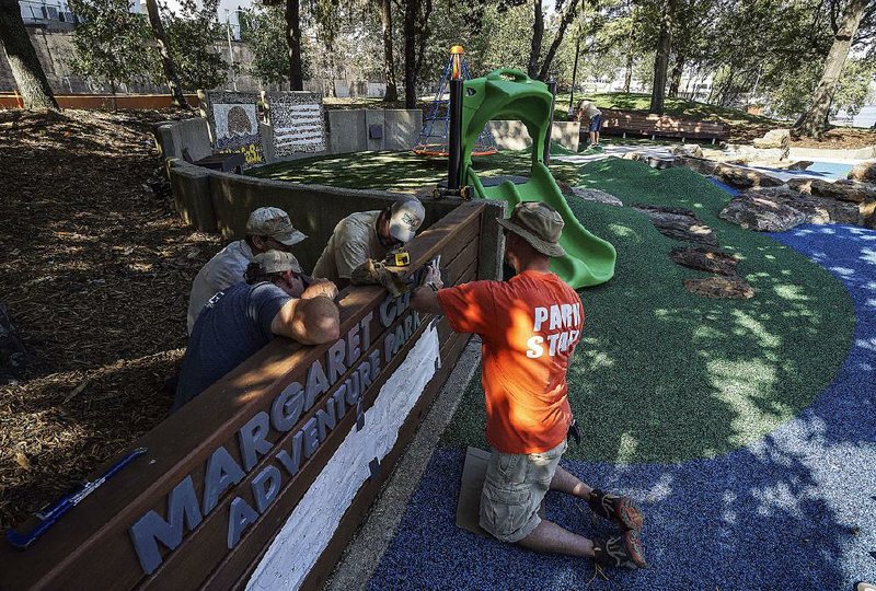 Little Rock Parks and Recreation employees put the finishing touches on the sign Thursday for the Margaret Clark Adventure Park in Little Rock. The park’s formal dedication will take place Saturday at 10 a.m. 