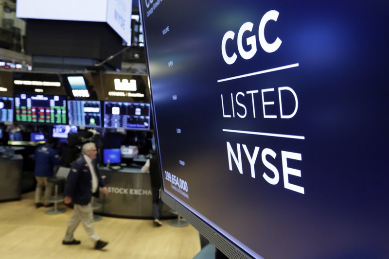In this May 31, 2018, file photo the logo for Canada's Canopy Growth Corp. appears on a screen above a trading post on the floor of the New York Stock Exchange. Investors are craving marijuana stocks as Canada prepares to legalize pot next month, leading to giant gains for Canada-based companies listed on U.S. exchanges. (AP Photo/Richard Drew, File)