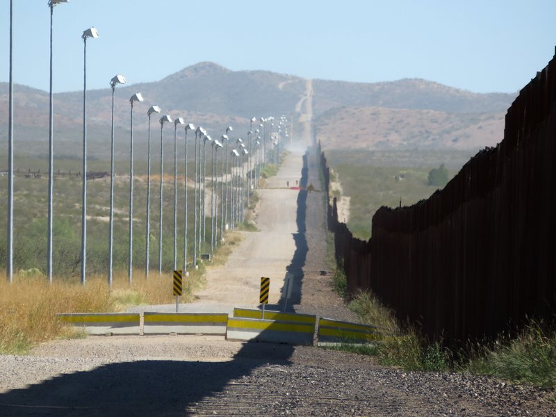 In this Nov. 15, 2016, photo provided by Kenneth Madsen, stadium lights atop tall poles oversee a pedestrian barrier stretching for miles along a section of the border wall between Douglas, Arizona, and Agua Prieta, in the Mexican state of Sonora.  (Kenneth Madsen via AP)