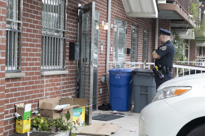 A police officer stands guard at the house were five people were stabbed overnight is seen, Friday, Sept. 21, 2018, in New York. Police say five people, including three infants, were stabbed at an overnight day care center in New York City. (AP Photo/Mary Altaffer)