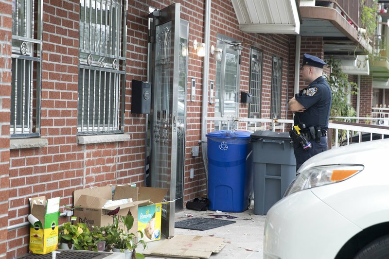 A police officer stands guard at the house were five people were stabbed overnight is seen Friday, Sept. 21, 2018, in New York. 