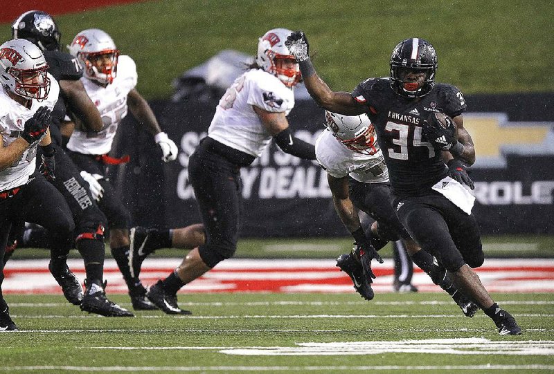 Arkansas State running back Marcel Murray (34) runs the ball through UNLV defenders during the first quarter Saturday at Centennial Bank Stadium in Jonesboro. Murray ran for 95 yards and 1 touchdown in the Red Wolves’ 27-20 victory.