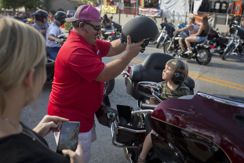 File Photo Dave Kemp of Kansas City, Mo., puts a helmet on Kellan Hale, 4 of Fayetteville during last year's Parade of Power. Tommy Sisemore, executive director of Bikes, Blues &amp; BBQ, says the rally always had a goal of being family friendly.