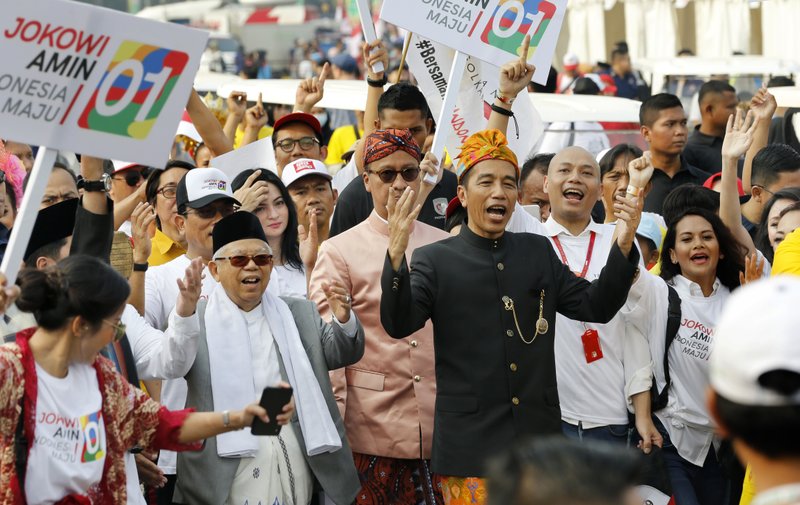 Indonesian President Joko Widodo, center right, walks and his running mate Ma'ruf Amin during a ceremony marking the kick off of the campaign period for next year's election in Jakarta, Indonesia, Sunday, Sept. 23, 2018. Indonesia is set to hold its presidential and parliamentary election poll in April 2019.(AP Photo/Tatan Syuflana)