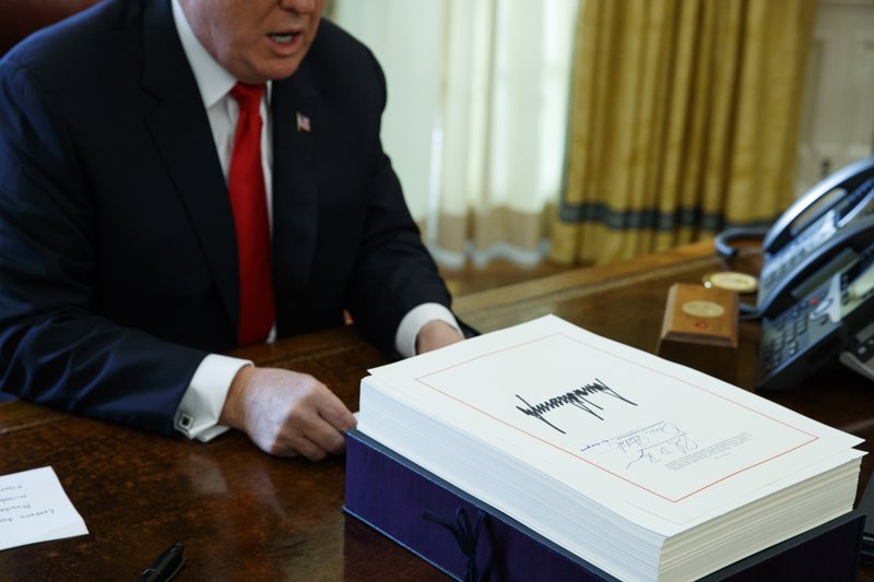 FILE- In this Dec. 22, 2017, file photo President Donald Trump speaks with reporters after signing the tax bill and continuing resolution to fund the government in the Oval Office of the White House in Washington. Employers who offer paid family and medical leave to their workers earning up to $72,000 a year can receive tax credits under the new tax law, the government has affirmed. The Treasury Department issued guidelines Monday, Sept. 24, 2018, for the tax credit, which is available to employers for leave paid this year and next. (AP Photo/Evan Vucci, File)