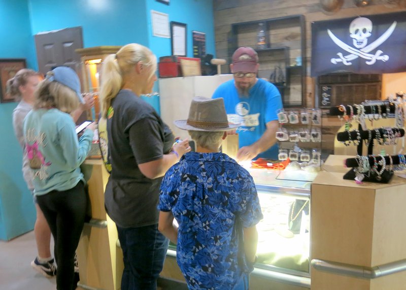 Photo by Susan Holland Paul Linscott, owner of the Old Spanish Treasure Cave with his wife Tracy, assists shoppers in the gift shop at the cave. Students from Arkansas Connections Academy and their families enjoyed a field trip to the cave to open their school year and several purchased souvenirs from the rock shop as mementoes of the occasion.