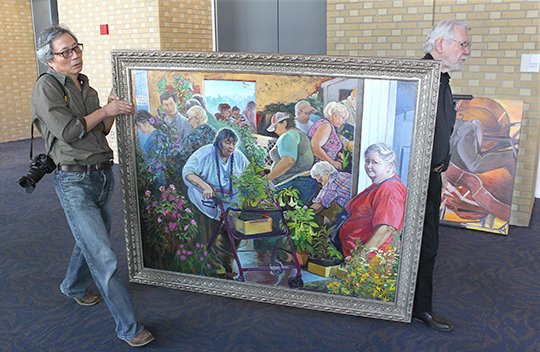 The Sentinel-Record/Richard Rasmussen MOVING DAY: Artist Longhua Xu, left, and Gary Simmons carry Xu's painting titled "Small Town Master Gardeners" down the north concourse of the Hot Springs Convention Center on Tuesday. The Hot Springs artist was at the center hanging his "The Soul of Arkansas" exhibit featuring 40 paintings which is set to open to the public Oct. 5.