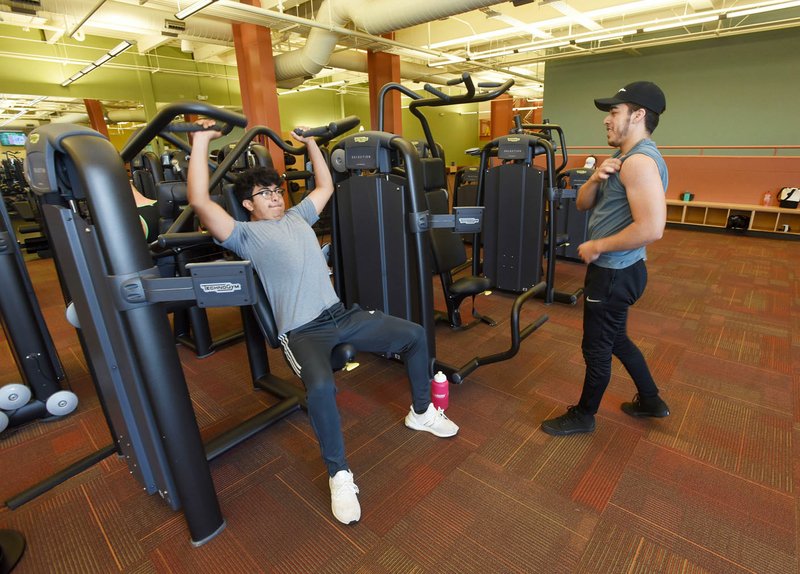 NWA Democrat-Gazette/FLIP PUTTHOFF Alex Arroyo (left) and Alan Pasillas work out Tuesday at the fitness center inside the Bentonville Community Center. The city of Bentonville may replace much of the current exercise equipment with new machines because of heavier than expected use of the community center.