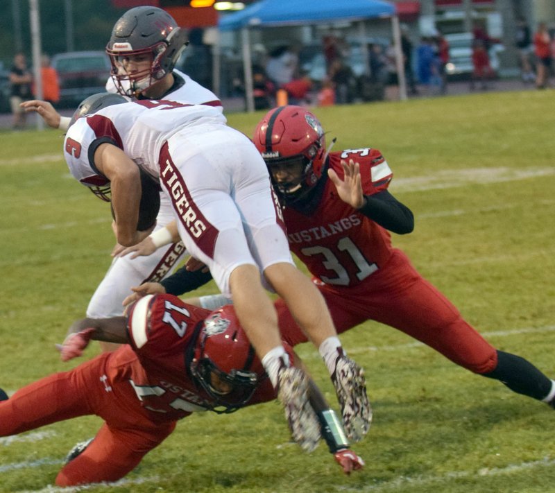 RICK PECK/SPECIAL TO MCDONALD COUNTY PRESS McDonald County's Trent Alik (17) and Michael Williams (31) team up to stop Nevada's Kaden Denny during the Mustangs' 42-2 win over the Tigers on Sept. 21 at MCHS.
