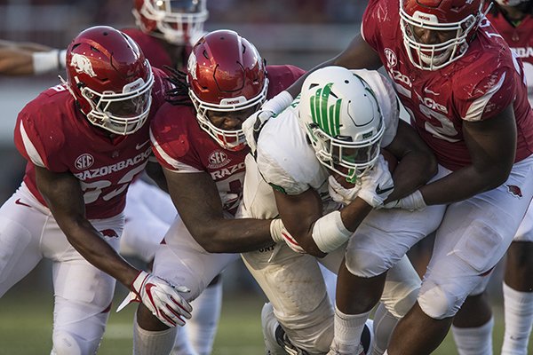 Arkansas defenders (from left) Dee Walker, Armon Watts and T.J. Smith tackle North Texas running back Loren Easly during a game Saturday, Sept. 15, 2018, in Fayetteville. 