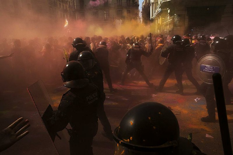 Catalan separatists toss and spray colored powder as they clash with police Saturday in Barcelona, Spain, during a march in support of independence for the region. Another group of marchers calling for the merging of the Spanish national police and the Civil Guard also turned out, leading to violent confrontations, officials said. “The separatists are kicking us out,” said national police officer Ibon Dominguez.