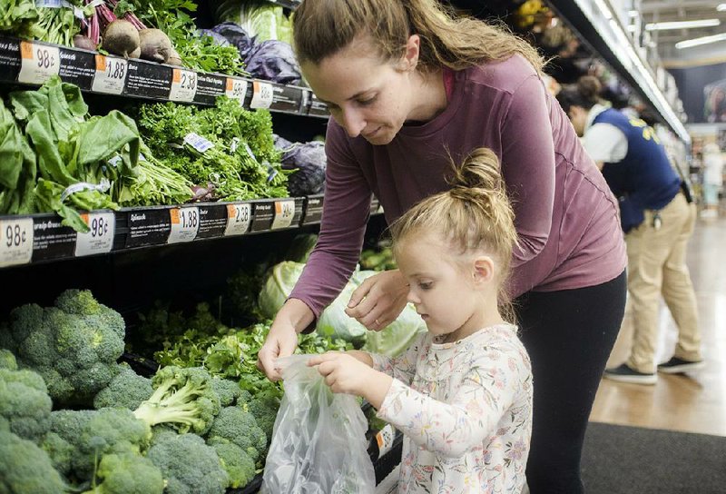 Courtney Bell of Rogers and Zola Luman, 3, pick out vegetables Thursday at the Walmart on South Pleasant Crossing Boulevard in Rogers. Walmart is soon to require suppliers of leafy greens to use new technology so foods can be traced in the event of an illness outbreak.