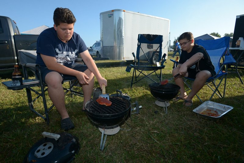 NWA Democrat-Gazette/ANDY SHUPE Brett Backerman, 13, (left) and his brother, Cole Backerman, 11, turn their boneless pork tenderloins on their grills Saturday during a Kids Q, a barbecue competition for children, as a part of the Bikes, Blues &amp; BBQ motorcycle rally at the Washington County Fairgrounds in Fayetteville.
