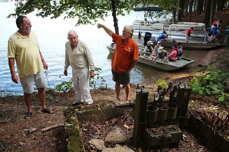 Gary Altenburger (from left), Gene Altenburger and Lloyd Hosier notice an old apparatus Sept. 21 near one of two trailheads of the Electric Island Nature Trail as behind them more visitors arrive to check out the new hiking path in the middle of Lake Hamilton. 