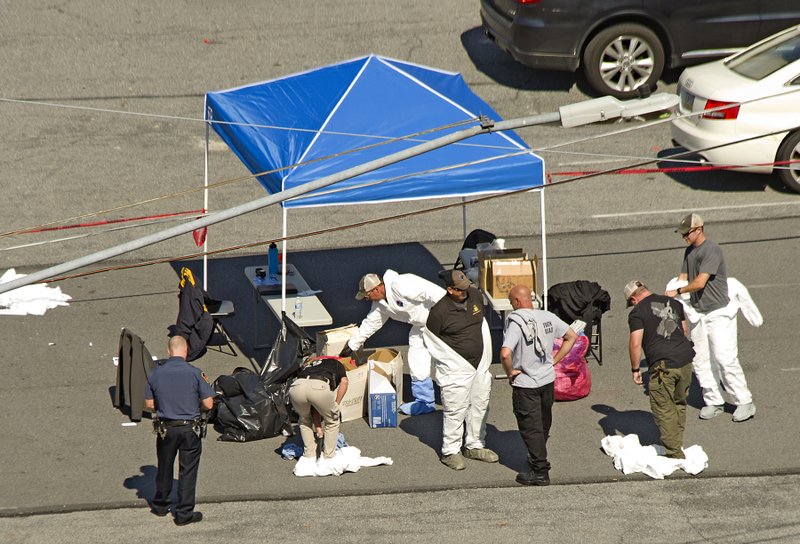 Police join members of the ATF and the FBI work in a parking lot off North 7th Street in Allentown, Pa., hours after a fiery car explosion rocked the neighborhood on Saturday. Police confirmed at least one fatality and at least 50 investigators remain on the scene scouring for evidence.  (Harry Fisher/The Morning Call via AP)