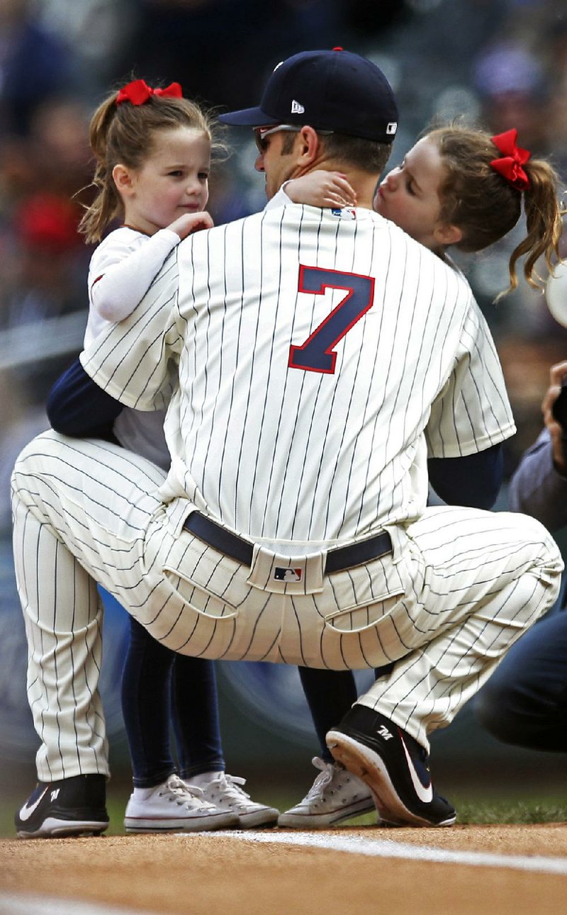 Joe Mauer of the Minnesota Twins is accompanied at first base by his twin daughters before Sunday’s game against the Chicago White Sox in Minneapolis. Mauer, the subject of retirement talk, hasn’t said whether he’ll return next season.