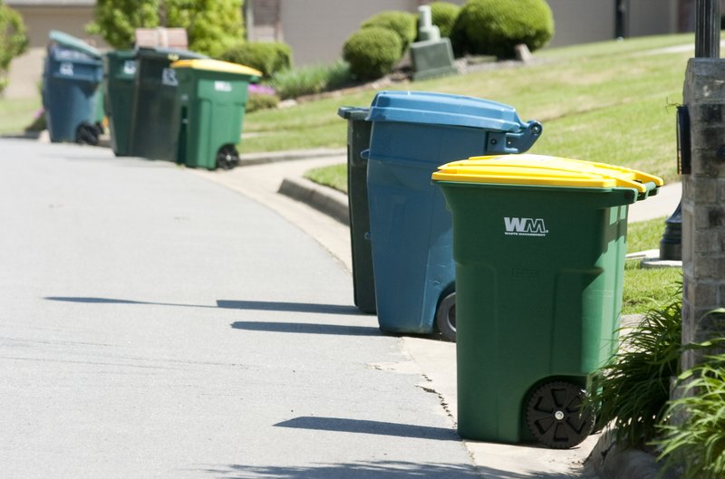 Recycling cans are lined up next to regular trash cans on Maisons Drive in Little Rock in this file photo.